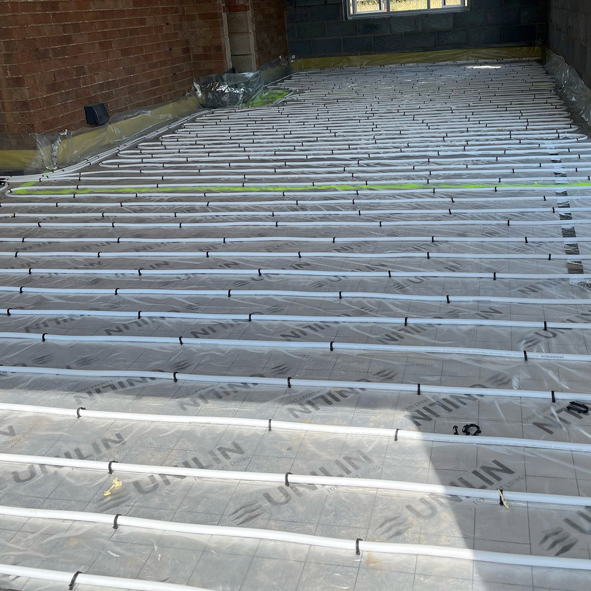 Water underfloor heating pipe arranged across a floor before covering