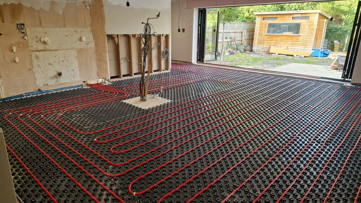 Large open-plan AD-TRAY water underfloor heating installation with red pipe laid across castellated trays