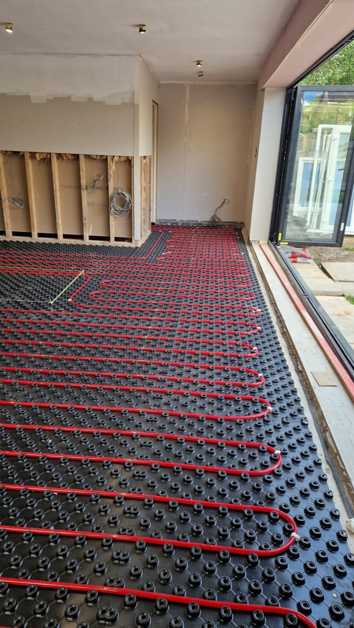 Close view of regular heating-pipe return bends clipped into AD-TRAY panels beside a doorway